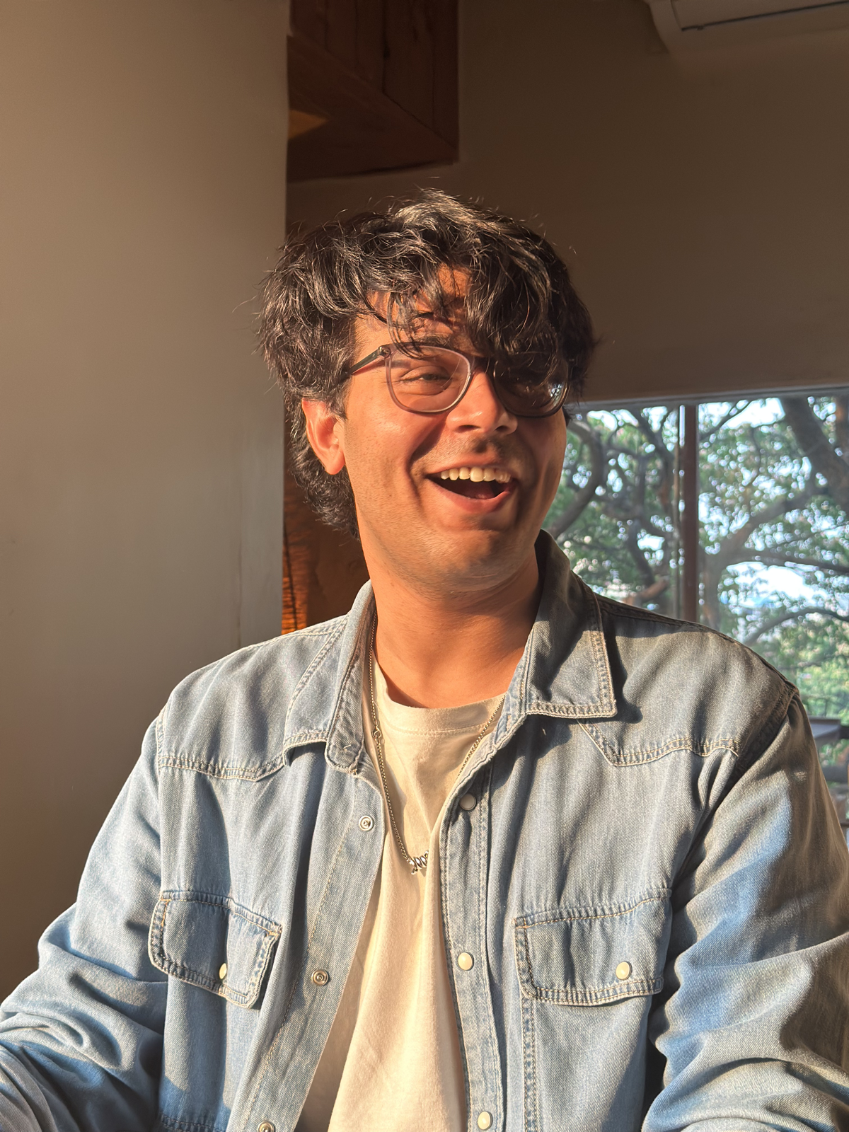Hishaam laughing in warm afternoon window light.