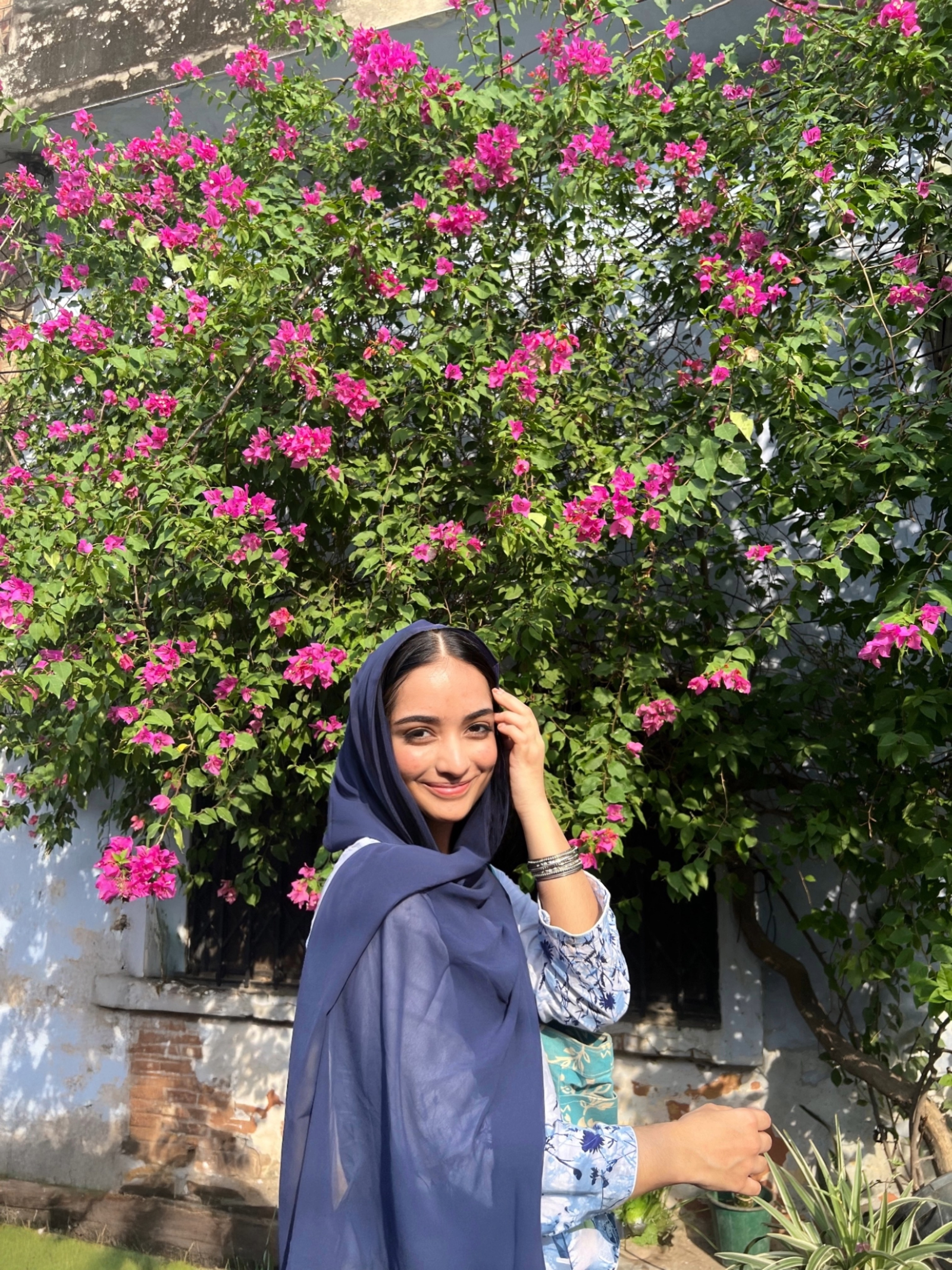 Vaniya smiling in front of bright bougainvillea.